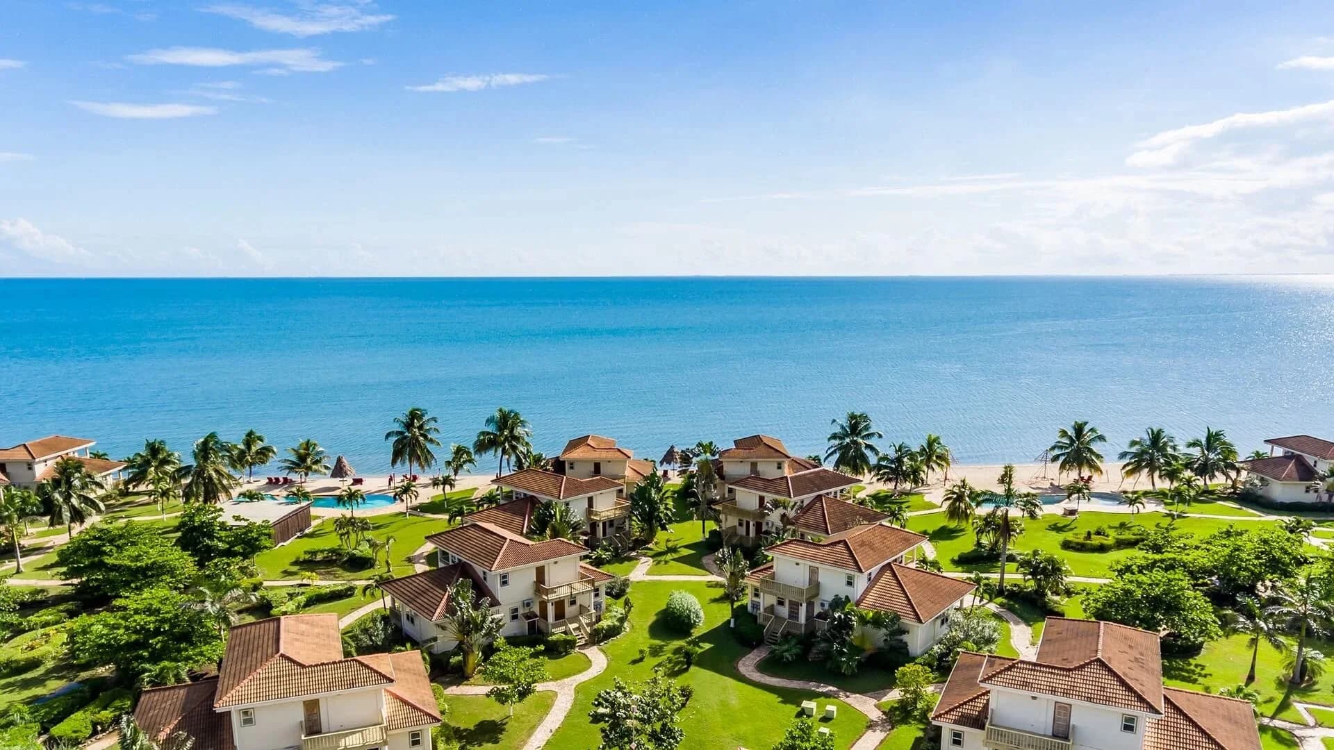 Aerial view of Hopkins Bay Belize's two-story, terracotta-roofed beach houses lining the Caribbean shoreline