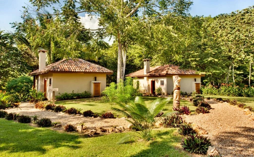 Two terracotta roofed Mystic River Resort casitas surrounded by tropical gardens and rainforest