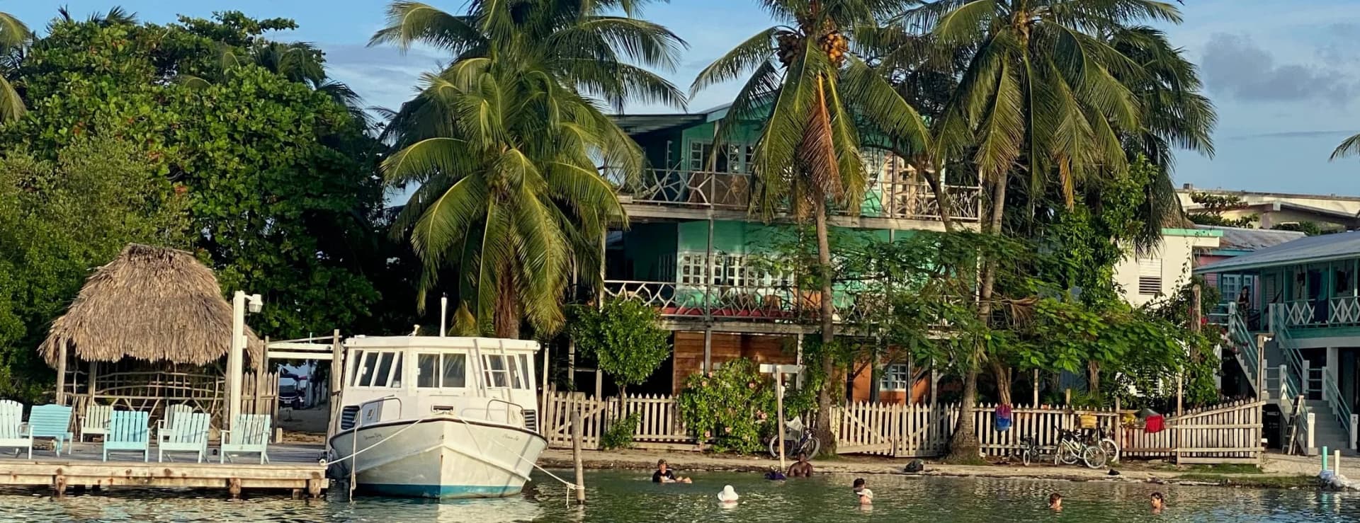 Waterfront exterior of Sea Dreams Hotel with wooden dock, palm trees, and guest buildings on Caye Caulker, Belize