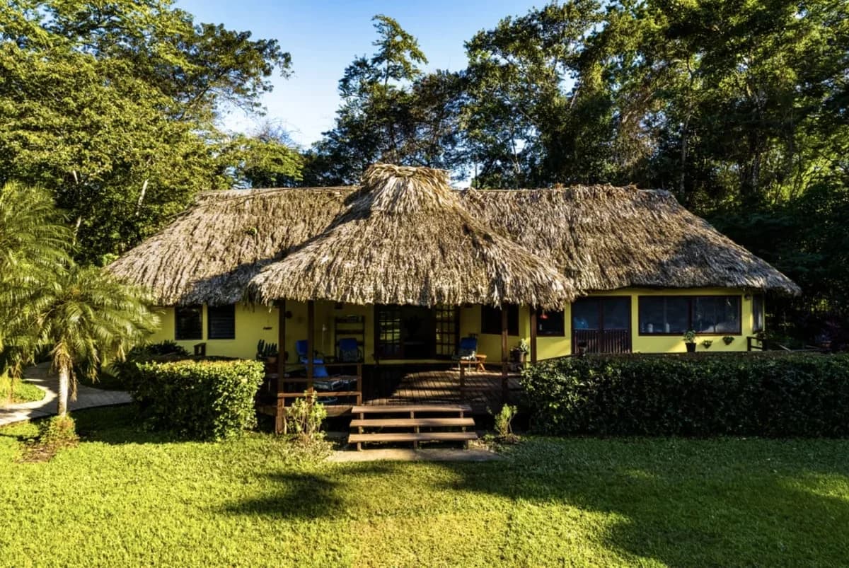 Tanager Rainforest Lodge's main palapa-thatched lodge building fronted by open lawn and rainforest, Big Falls, Toledo